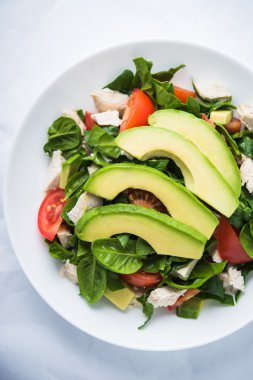 Taze salata tavuk, domates, ıspanak ve beyaz arka plan üstten görünüm üzerinde avokado. Sağlıklı gıda.