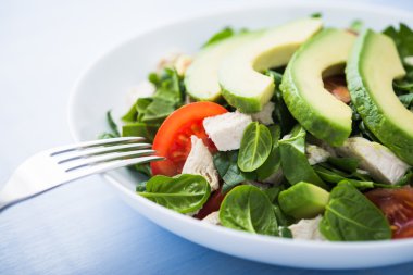 Taze salata tavuk, domates, ıspanak ve avokado mavi ahşap zemin üzerine kapatın. Sağlıklı gıda.