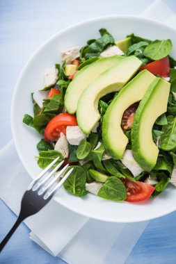 Taze salata tavuk, domates, ıspanak ve mavi ahşap arka plan üstten görünüm üzerinde avokado. Sağlıklı gıda.
