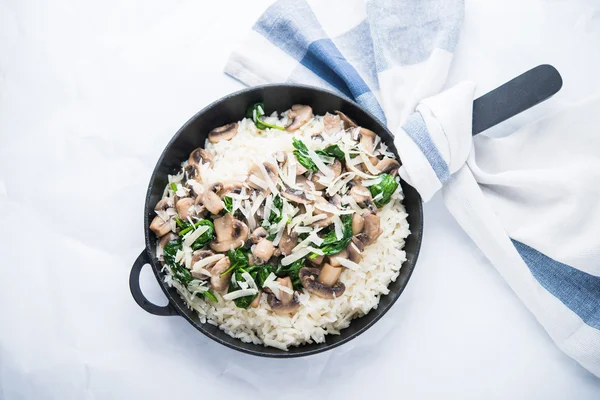 Rice (risotto) with mushrooms, parmesan and spinach top view on white background. Italian cuisine.