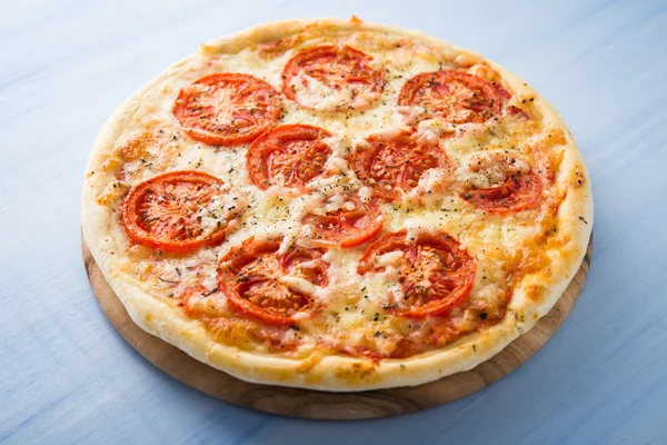 Pizza con pomodoro, formaggio e basilico secco su fondo blu in legno da vicino. Cucina italiana. — Foto Stock
