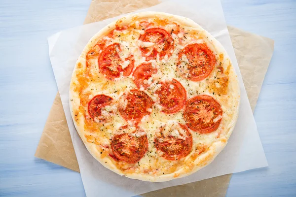 Pizza mit Tomate, Käse und trockenem Basilikum auf blauem Holzhintergrund von oben. Italienische Küche. — Stockfoto