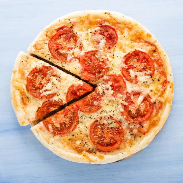 Pizza con pomodoro, formaggio e basilico secco su fondo blu in legno vista dall'alto. Cucina italiana . — Foto Stock