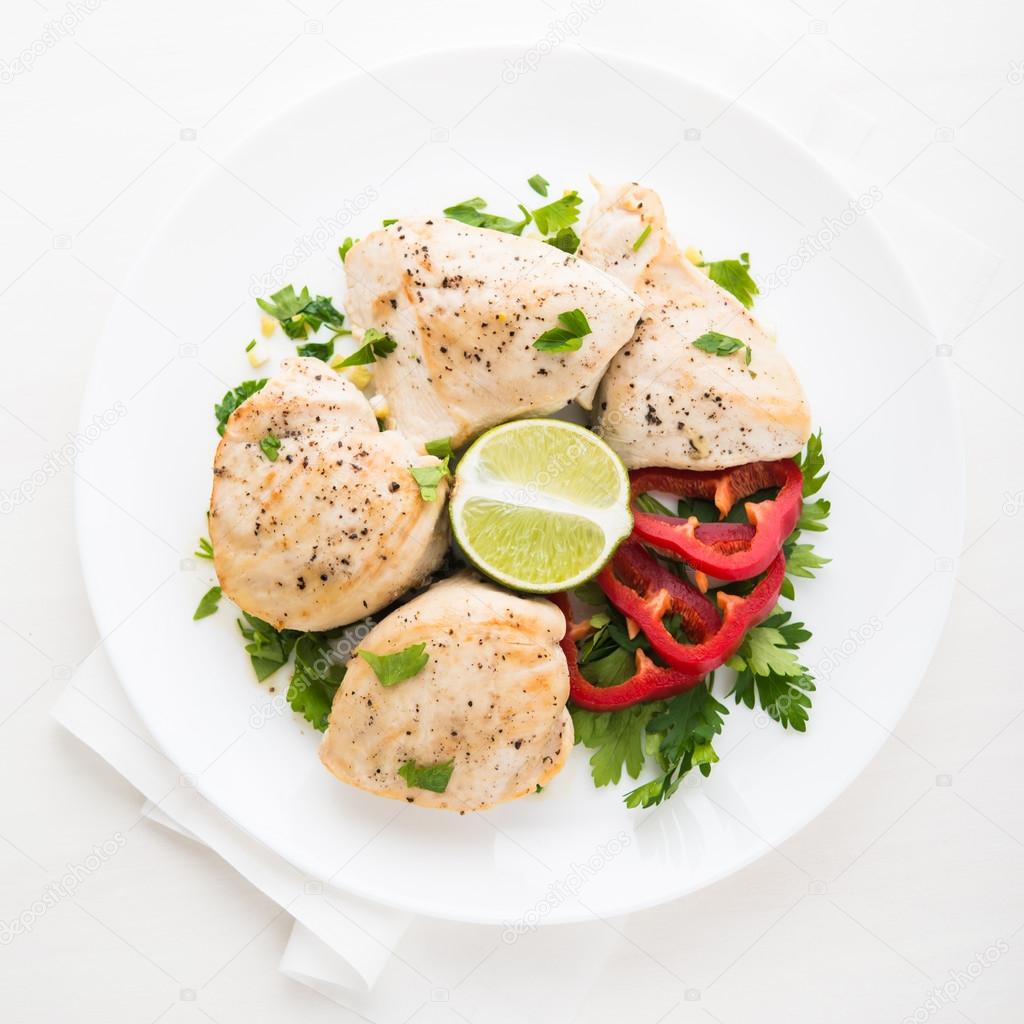 Chicken breasts with parsley, pepper and citrus on white wood background top view. Healthy food.