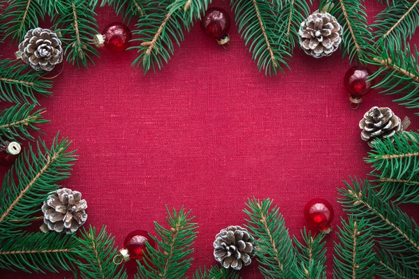 Moldura com árvore de xmas e ornamentos em fundo de tela vermelha — Fotografia de Stock