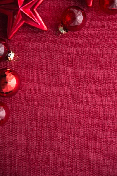 Red christmas decorations (stars and balls) on red canvas background — Stock Photo, Image