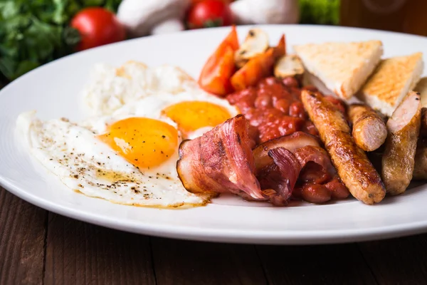 Англійський сніданок (яйця пашот, квасоля, смажений бекон, сосиски і овочі) крупним планом — стокове фото