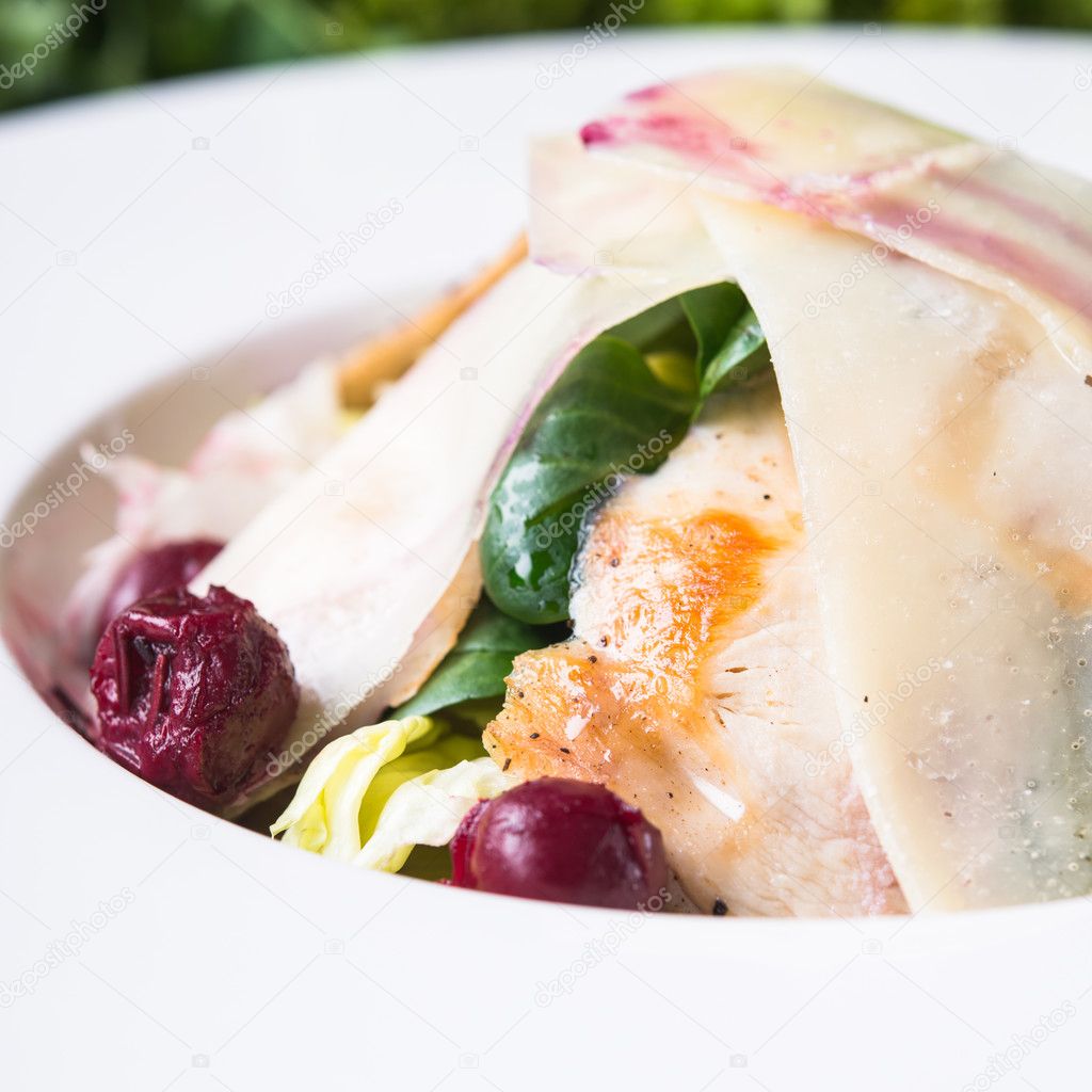 Fresh salad with chicken, parmesan, greens and cherry on wooden background close up