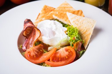 Ahşap arka plan üzerinde yumurta, domates, pastırma ve marul ile taze salata yakın