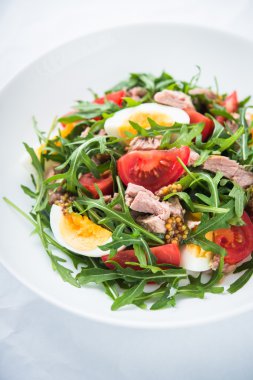 Ton balığı, domates, yumurta, arugula ve hardal ile taze salata beyaz dokulu arka plan yakın