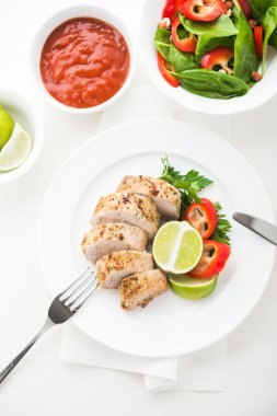 Beyaz arka planda ıspanak salatası ile dilimlenmiş limon domuz bonfile