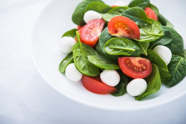 Beyaz kağıt arka plan üzerinde mozzarella peyniri, domates ve ıspanak ile taze salata yakın