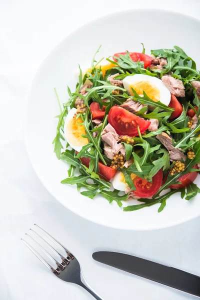 Färsk sallad med tonfisk, tomater, ägg, ruccola och senap på vit texturerad bakgrund uppifrån — Stockfoto