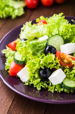 Yunan salatası (marul, domates, beyaz peynir, salatalık, siyah zeytin) koyu ahşap arka plan üzerinde yakın.