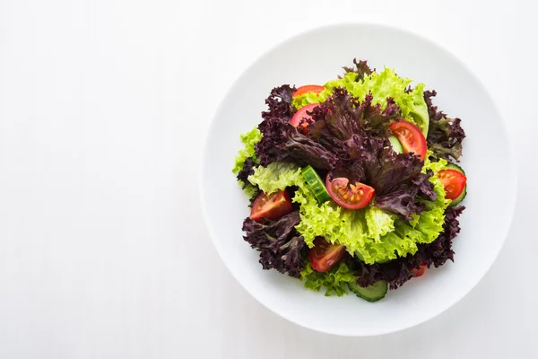 Salad segar dengan selada hijau dan ungu, tomat dan mentimun pada pemandangan atas kayu putih . — Stok Foto