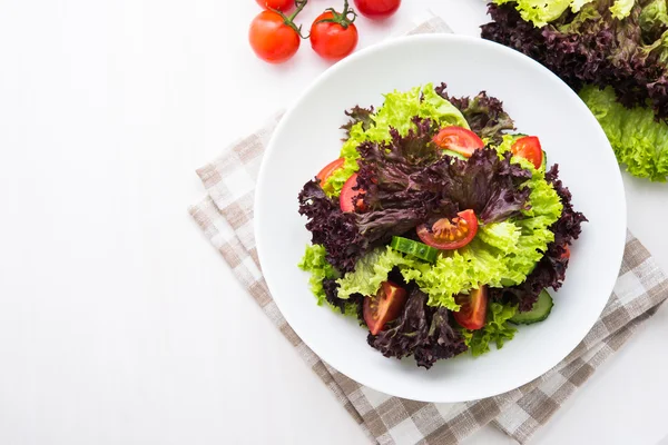 Salad segar dengan selada hijau dan ungu, tomat dan mentimun pada pemandangan atas kayu putih . — Stok Foto