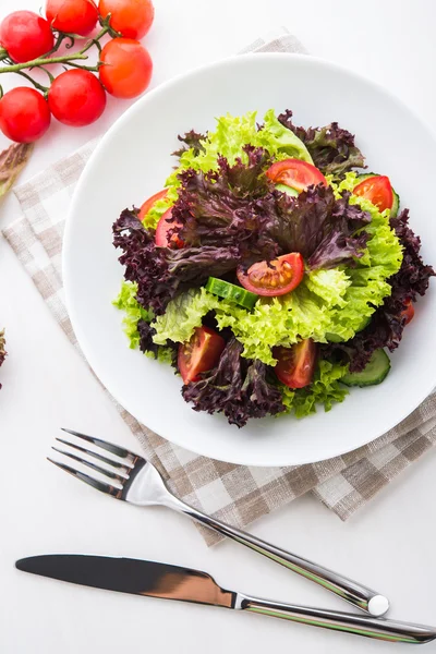 Salada fresca com alface verde e roxa, tomate e pepino sobre fundo branco de madeira vista superior . — Fotografia de Stock