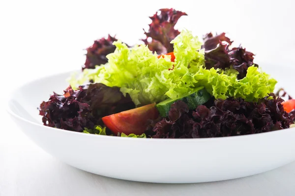 Salada fresca com alface verde e roxa, tomates e pepinos em fundo de madeira branca close up . — Fotografia de Stock