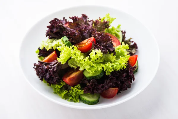 Salade fraîche avec laitue verte et violette, tomates et concombres sur fond de bois blanc fermer . — Photo