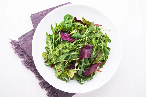 Salad segar dengan campuran hijau (arugula, mesclun, mache) pada tampilan atas kayu putih . — Stok Foto