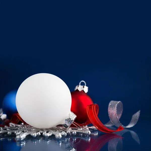 White, silver and red christmas ornaments on dark blue background with space for text. Merry christmas card — Stok fotoğraf