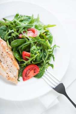 Kavrulmuş tavuk göğsü ve domates ve yeşillik (ıspanak, arugula) beyaz ahşap arka plan üzerinde üst görünümü ile taze salata.