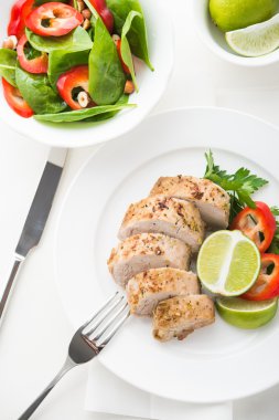 Beyaz arka plan üzerinde üstten görünüm kireç domuz eti bonfile ıspanak salatası ile dilimlenmiş.