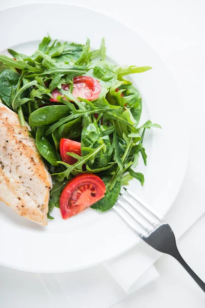 Kavrulmuş tavuk göğsü ve domates ve yeşillik (ıspanak, arugula) beyaz ahşap arka plan üzerinde üst görünümü ile taze salata.