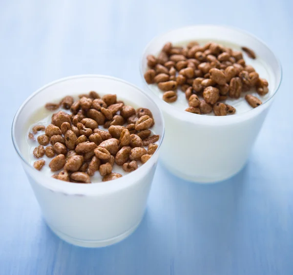 Tazas de yogur con cereales sobre fondo azul (desayuno saludable) ) — Foto de Stock