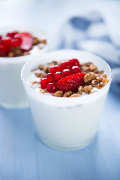 Iogurte com cereais e bagas em fundo azul (café da manhã saudável ) — Fotografia de Stock