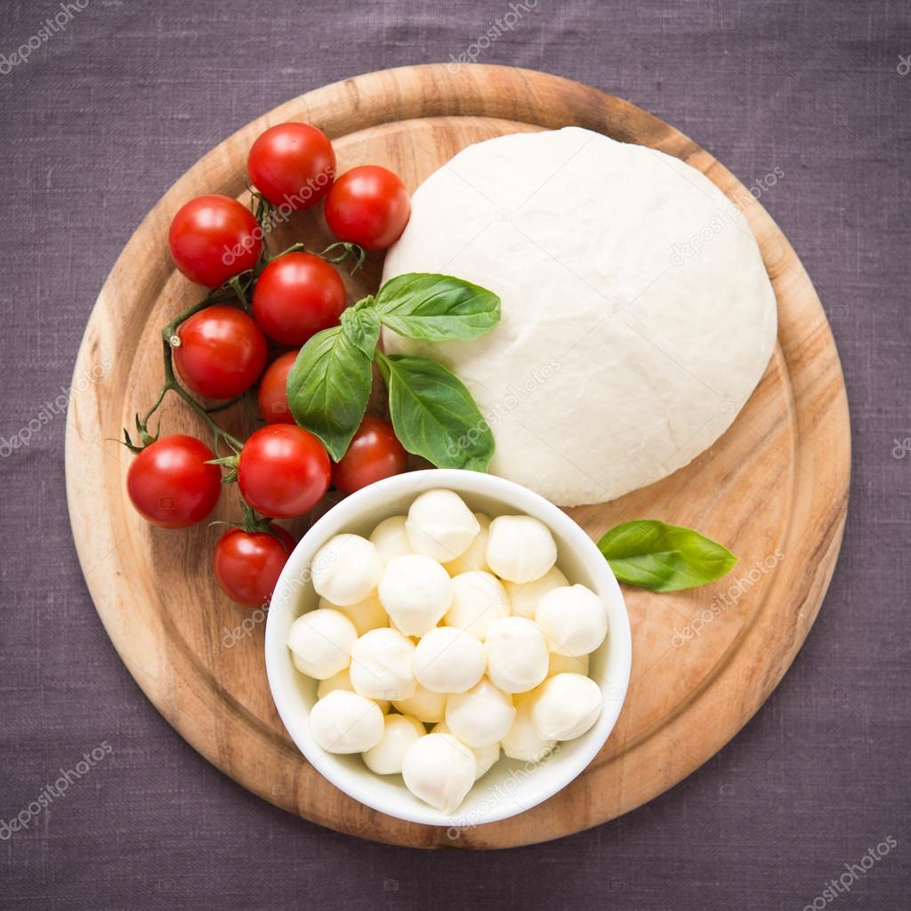 Ingredients for pizza margherita on wooden plate top view