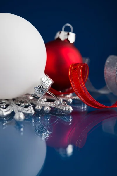 Ornamenti natalizi bianchi, argento e rossi su sfondo blu scuro con spazio per il testo . — Foto Stock