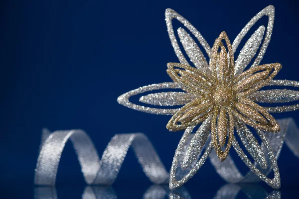 Christmas holiday snowflake and silver ribbon on dark blue background — Stock Photo, Image