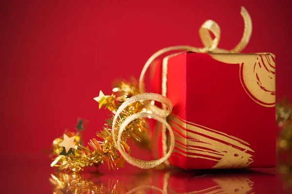 Rode geschenkdoos met gouden linten op rode achtergrond. Vrolijk kerstfeest. — Stockfoto