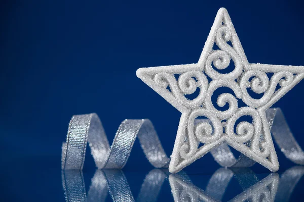 Stella di Natale bianca con nastro d'argento su sfondo blu con spazio per il testo. Tema vacanze di Natale . — Foto Stock