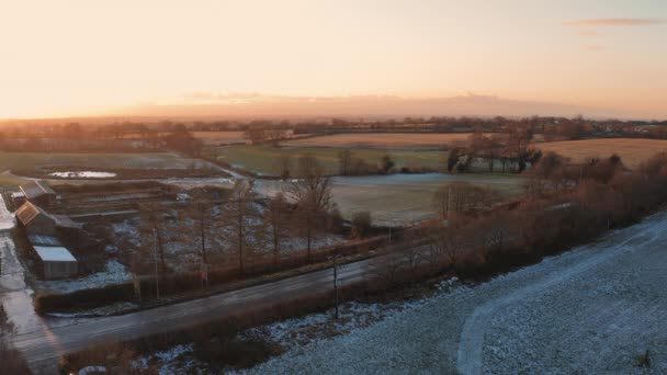 Cheshire, Reino Unido - 29 de diciembre de 2020: Vista aérea del supermercado Morrisons furgoneta de reparto conduce por un frío campo congelado cubierto de nieve frente a una hermosa puesta de sol — Vídeo de stock