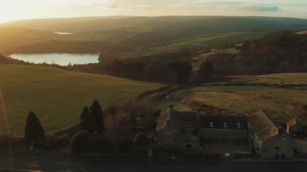 Letecký sklon 4K, který vytváří záběr na statek v národním parku Peak District. Letní západ slunce s jezerem a lesním pozadím — Stock video