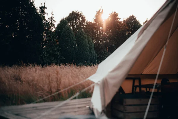 À l'intérieur d'une tente cloche utilisée pour le glamping et le camping dans un long champ d'herbe avec le coucher de soleil derrière la tente — Photo