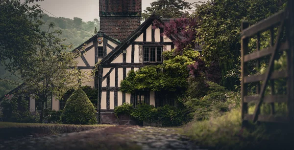 Ancienne maison vintage Tudor le long d'une allée de gravier derrière une porte Images De Stock Libres De Droits