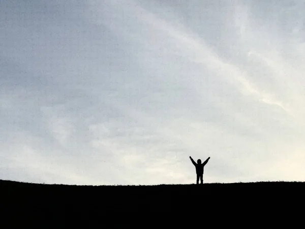 Silhouette of a man on top of a mountain. Man is not a background of earth and sky. Silhouettes of people in the distance on the hill.