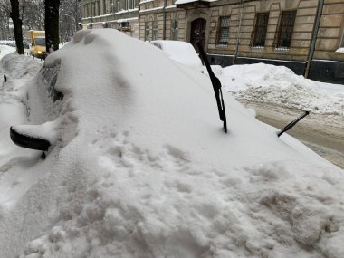 Araba otoparkta karla kaplıydı. Büyük bir kar tabakasının altında arabalar. Bir Avrupa şehrinin sokaklarına kar yağışı.