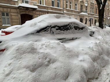 Araba otoparkta karla kaplıydı. Büyük bir kar tabakasının altında arabalar. Bir Avrupa şehrinin sokaklarına kar yağışı.