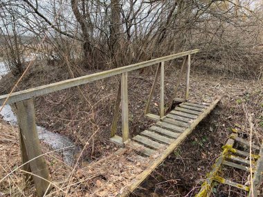 Küçük bir hendeğin üzerindeki tahta köprü. Nehrin karşısındaki kırsal köprü Ormandaki kanalı geçiyor.