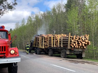 İtfaiyeciler ormanın yakınındaki bir kamyonu söndürüyor. Duman ve yangın kamyonun taksisinde. Odun taşıyıcı yangından dolayı duman içinde. Radomyshl Köyü, Zhytomyr bölgesi, Ukrayna 4 Mayıs 2021