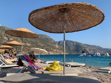 Kumsalda kumsal tatili. Şemsiyeli ve güneşli deniz plajı. Akdeniz 'de yaz tatili. Türkiye 'de Mavi Loguna, Oludeniz - Fetiya, 10 Temmuz 2021