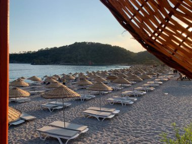 Kumsalda kumsal tatili. Şemsiyeli ve güneşli deniz plajı. Akdeniz 'de yaz tatili. Türkiye 'de Mavi Loguna, Oludeniz - Fetiya, 10 Temmuz 2021