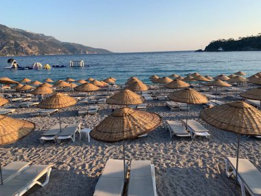 Kumsalda kumsal tatili. Şemsiyeli ve güneşli deniz plajı. Akdeniz 'de yaz tatili. Türkiye 'de Mavi Loguna, Oludeniz - Fetiya, 10 Temmuz 2021