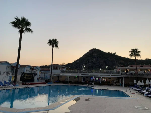 山と青空を背景にヤシの木 日没の夏の夜に背の高い熱帯の木 ホテルのプール Karbel Turkey Oludeniz August 2021 — ストック写真