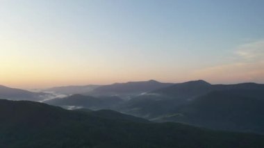 Gün batımında Karpat Dağları 'nın zirveleri. Dağlarda gün batımı, üst manzara. Orman ve dağlar kuş bakışı. Dağ sırası ve yeşil vadi.