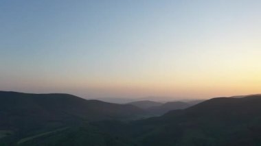 Gün batımında Karpat Dağları 'nın zirveleri. Dağlarda gün batımı, üst manzara. Orman ve dağlar kuş bakışı. Dağ sırası ve yeşil vadi.